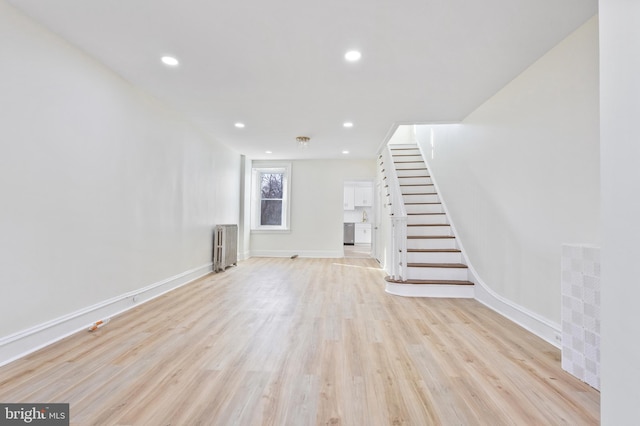 unfurnished living room featuring light wood-type flooring and radiator heating unit