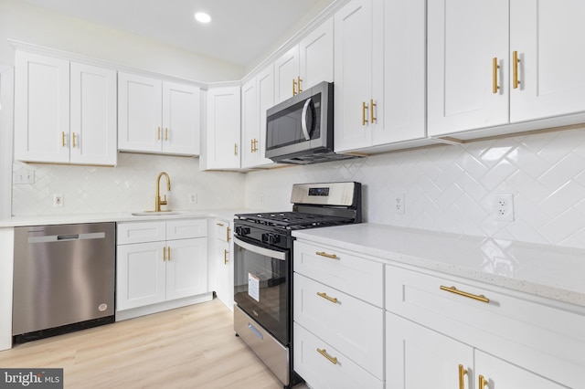 kitchen featuring sink, white cabinets, stainless steel appliances, and light hardwood / wood-style floors