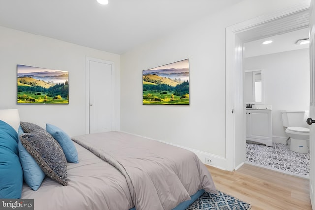 bedroom featuring hardwood / wood-style flooring and ensuite bathroom