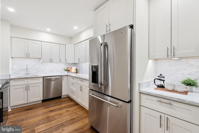 kitchen featuring sink, tasteful backsplash, dark hardwood / wood-style floors, white cabinets, and appliances with stainless steel finishes