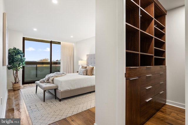 bedroom with expansive windows, access to exterior, and wood-type flooring