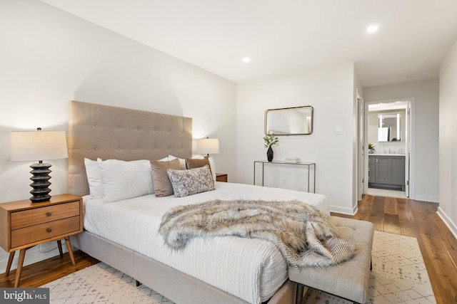 bedroom with hardwood / wood-style floors and ensuite bathroom