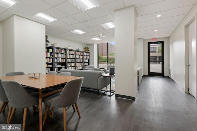 dining space with a drop ceiling and dark hardwood / wood-style flooring