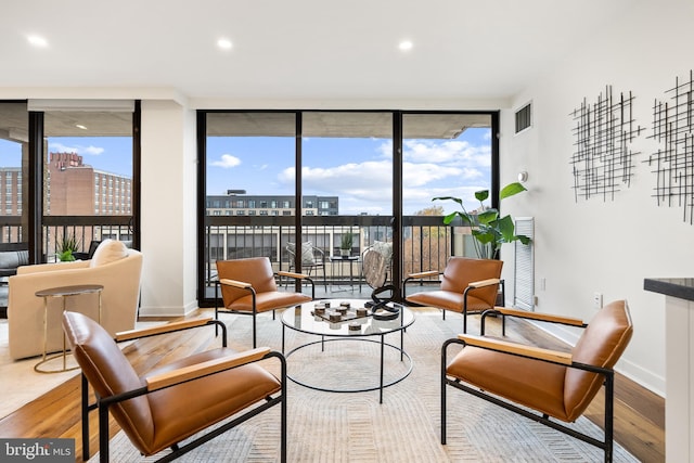 living area with light hardwood / wood-style floors and a wall of windows