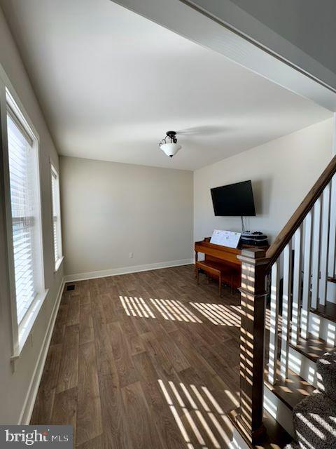 unfurnished living room with plenty of natural light and dark hardwood / wood-style flooring