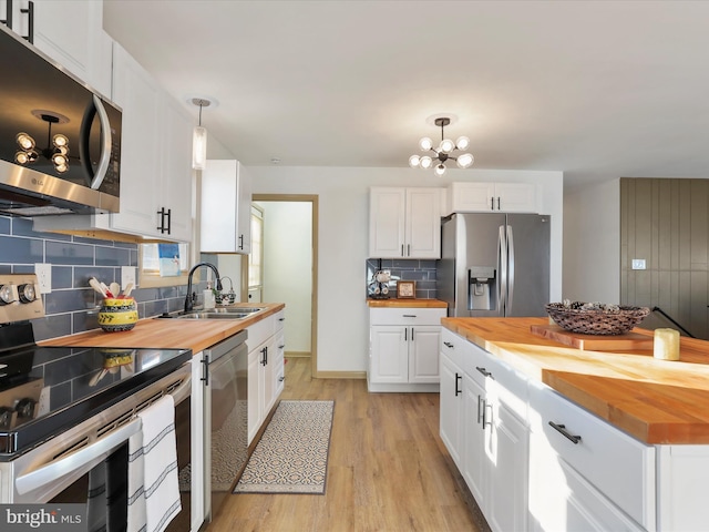 kitchen featuring white cabinetry, sink, stainless steel appliances, wood counters, and pendant lighting