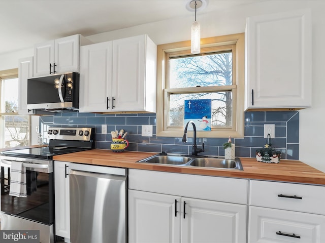 kitchen with white cabinets, pendant lighting, stainless steel appliances, and sink