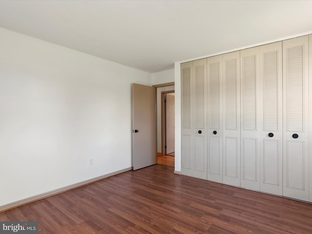 unfurnished bedroom with a closet and dark hardwood / wood-style floors