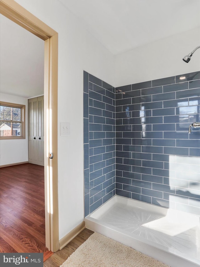 bathroom with hardwood / wood-style flooring and a tile shower