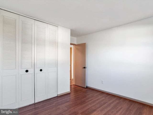 unfurnished bedroom with dark hardwood / wood-style floors and a closet