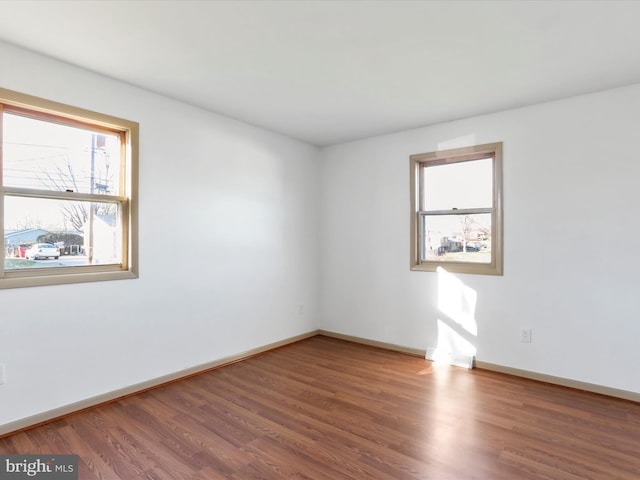 empty room with dark hardwood / wood-style floors and a healthy amount of sunlight