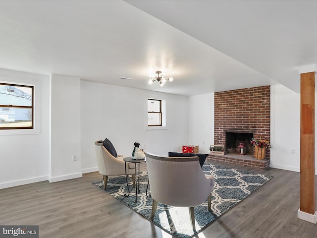 living room featuring a brick fireplace, dark wood-type flooring, and a notable chandelier