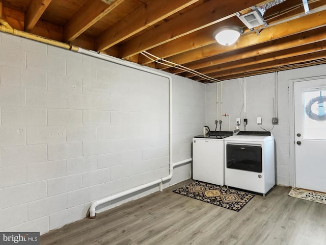 clothes washing area featuring washing machine and dryer and hardwood / wood-style flooring