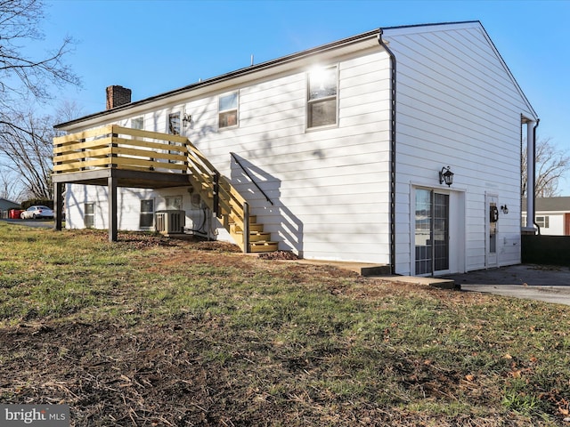 back of property featuring a yard, central AC unit, and a deck