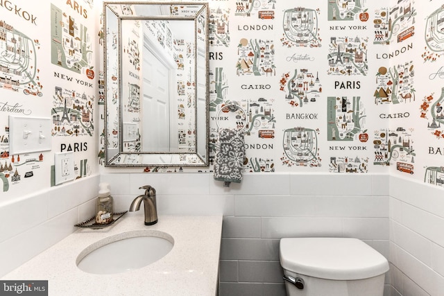 bathroom with sink, tile walls, and toilet