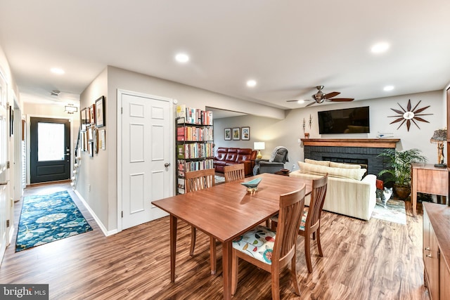 dining space featuring a fireplace, light hardwood / wood-style flooring, and ceiling fan