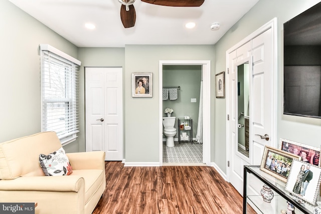 sitting room with dark wood-type flooring and ceiling fan