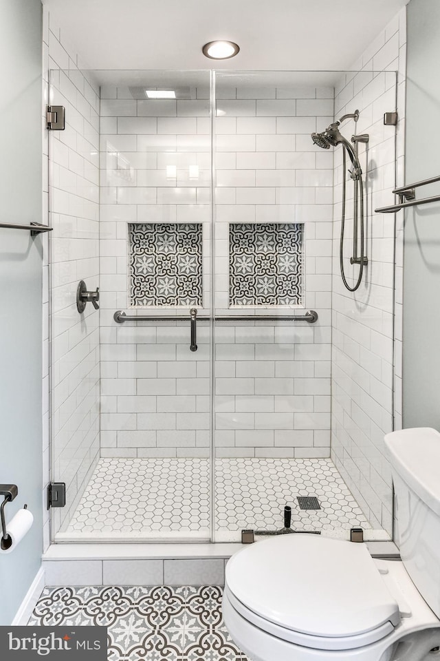 bathroom featuring an enclosed shower, tile patterned floors, and toilet