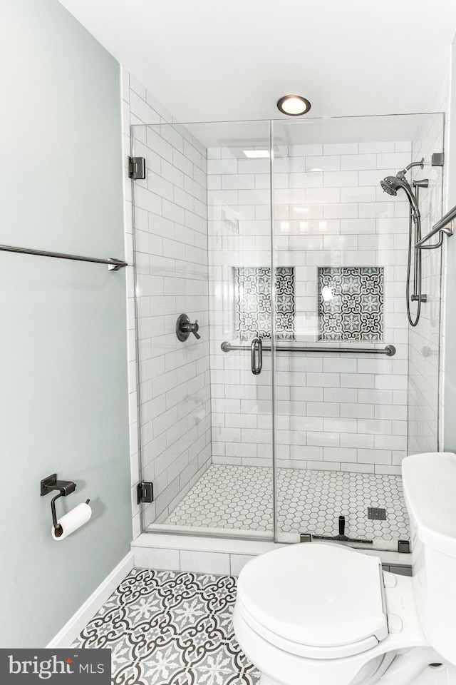 bathroom with tile patterned floors, toilet, and an enclosed shower