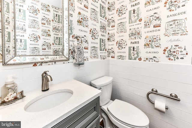 bathroom featuring vanity, tile walls, and toilet