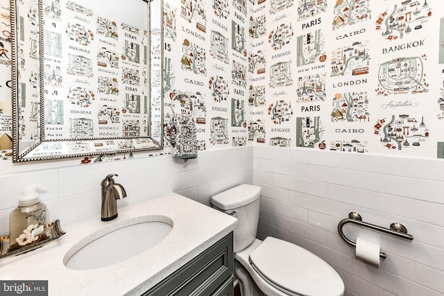 bathroom featuring vanity, tile walls, and toilet