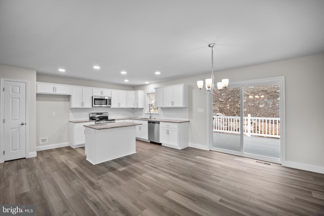 kitchen with appliances with stainless steel finishes, light wood-type flooring, a center island, and white cabinetry