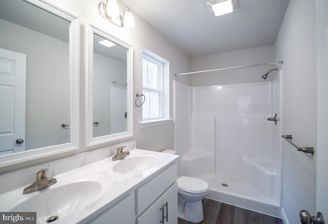 bathroom featuring wood-type flooring, vanity, toilet, and walk in shower