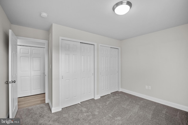 unfurnished bedroom with multiple closets and carpet