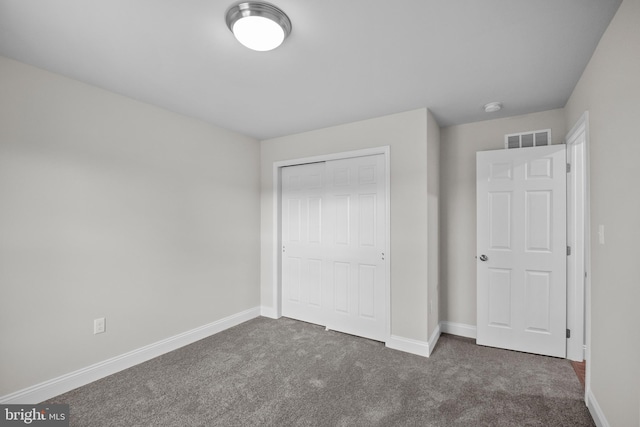 unfurnished bedroom with dark carpet and a closet