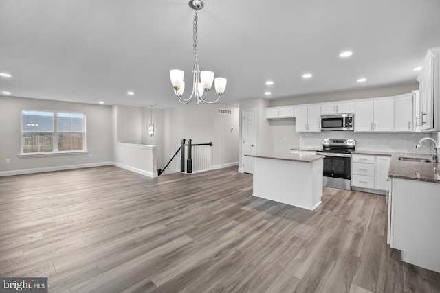 kitchen with sink, light wood-type flooring, a kitchen island, white cabinetry, and stainless steel appliances