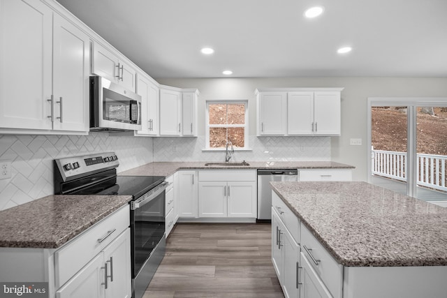 kitchen with light stone countertops, appliances with stainless steel finishes, a healthy amount of sunlight, and sink