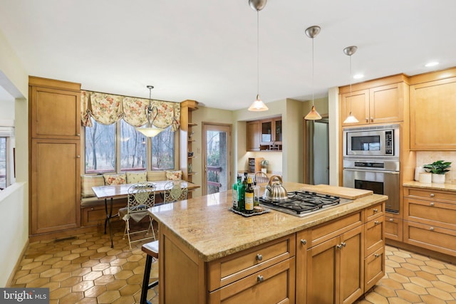 kitchen with light stone counters, stainless steel appliances, pendant lighting, a center island, and a breakfast bar area