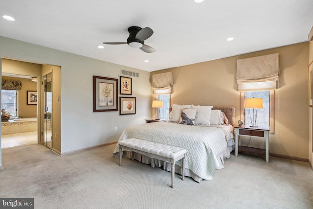 bedroom with ceiling fan, light carpet, and ensuite bath