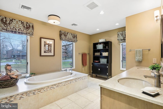 bathroom with tile patterned floors, vanity, and tiled tub