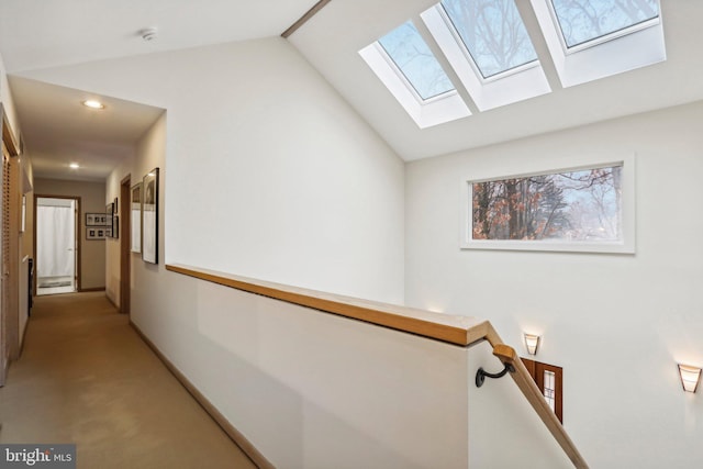 corridor with vaulted ceiling with skylight and light carpet