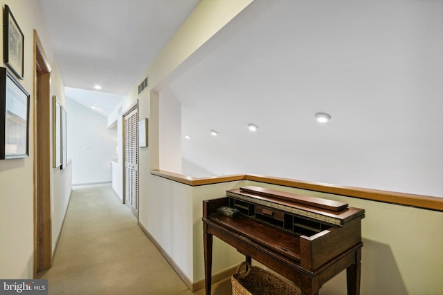 hallway with light colored carpet and lofted ceiling