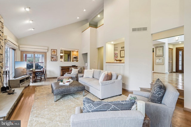 living room with light wood-type flooring and high vaulted ceiling