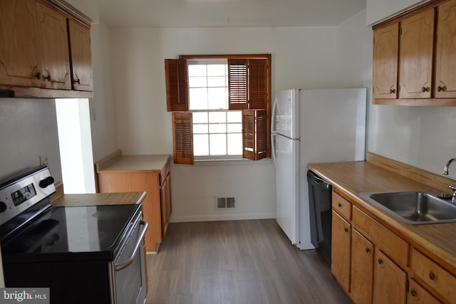 kitchen with sink, electric range, light hardwood / wood-style flooring, black dishwasher, and white fridge