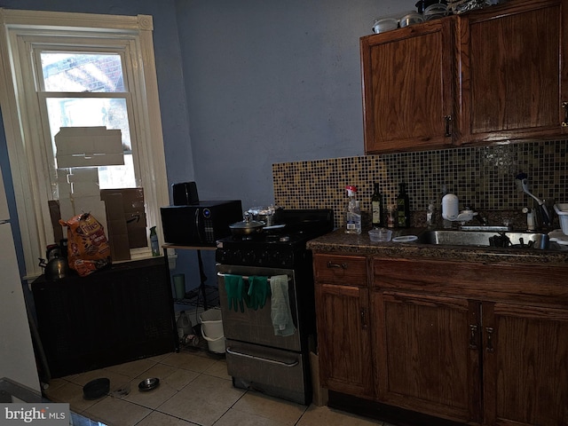 kitchen featuring backsplash, sink, black range, and light tile patterned flooring