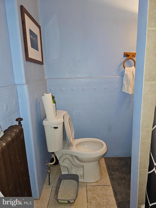 bathroom featuring tile patterned flooring, toilet, radiator heating unit, and tile walls