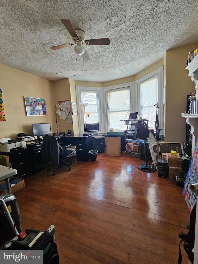 home office with dark hardwood / wood-style floors, ceiling fan, and a textured ceiling