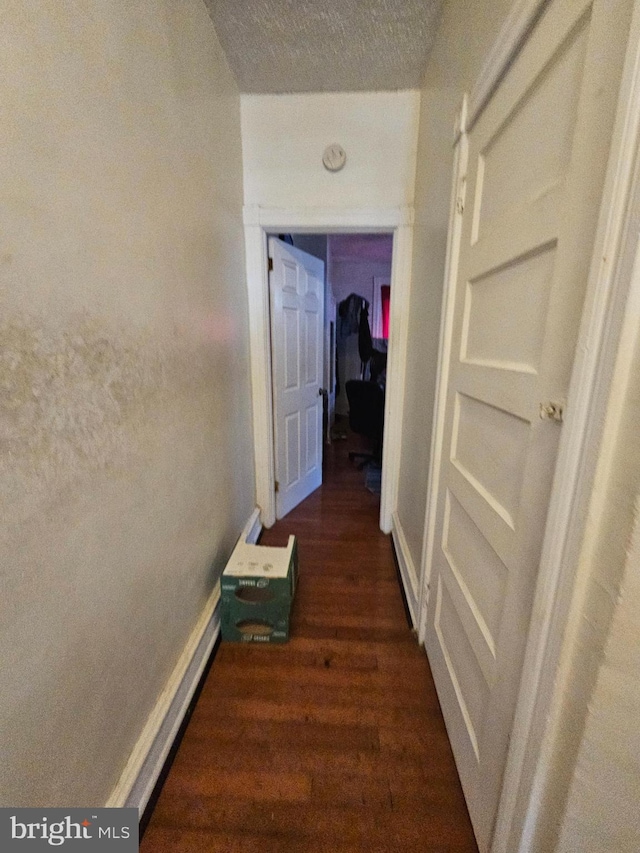 hallway with a textured ceiling and dark hardwood / wood-style flooring