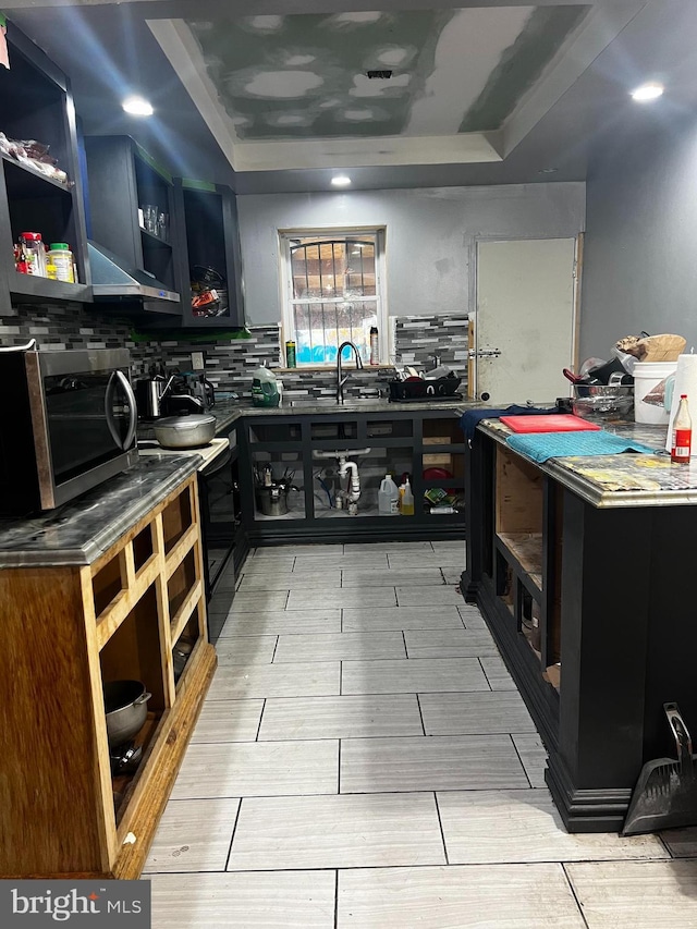 kitchen with backsplash, sink, electric range, light wood-type flooring, and a tray ceiling