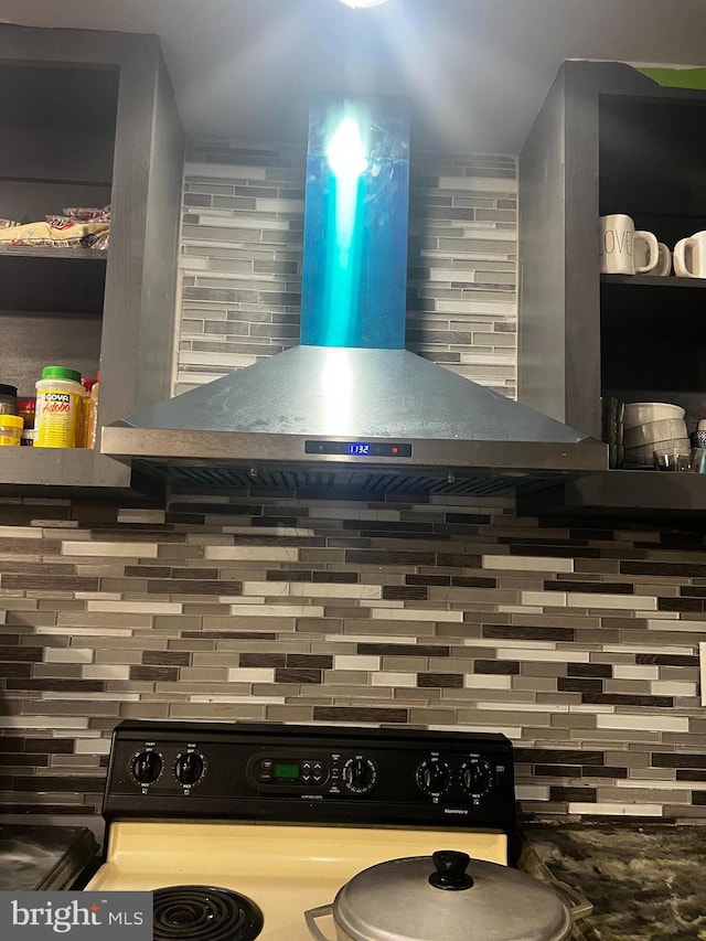 interior space with wall chimney range hood, backsplash, and black electric range