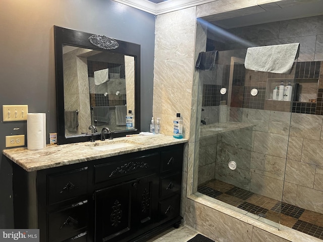 bathroom with a tile shower, vanity, and ornamental molding