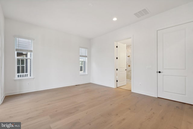 unfurnished bedroom with connected bathroom and light hardwood / wood-style flooring