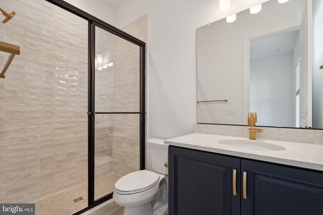 bathroom featuring vanity, toilet, and a shower with shower door