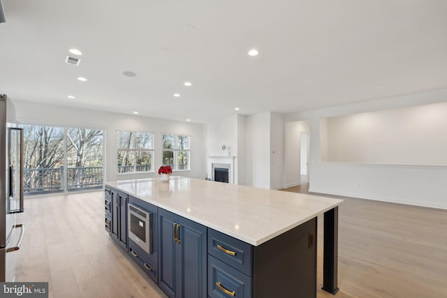 kitchen featuring a kitchen island, light wood-type flooring, blue cabinetry, and appliances with stainless steel finishes