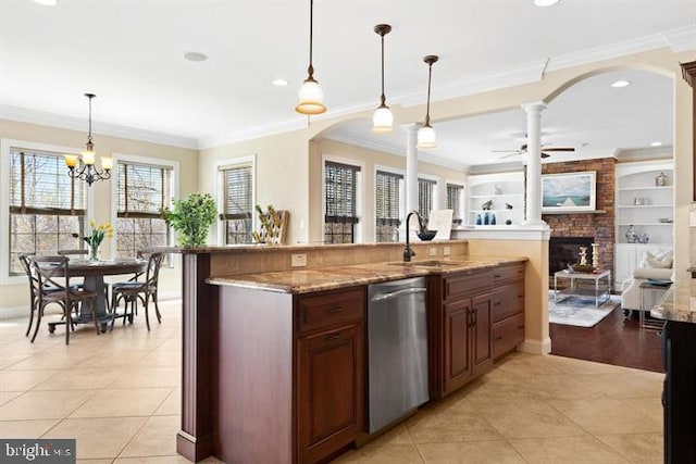 kitchen featuring stainless steel dishwasher, ceiling fan with notable chandelier, sink, decorative light fixtures, and a fireplace