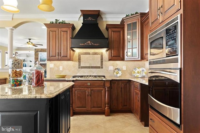 kitchen with stainless steel appliances, custom range hood, ornamental molding, light stone counters, and tasteful backsplash